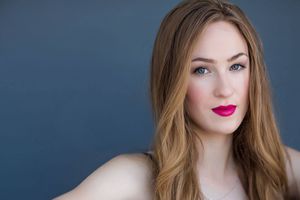 Beauty portrait with bright red lipstick against dark blue backdrop.