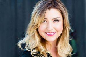 Glamour portrait with wavy blonde ombre hair against dark background.