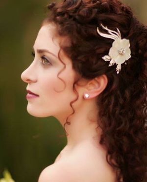 Side profile showing curly dark hair with decorative white hair accessory in romantic styling.