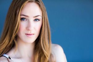 Professional portrait with straight light brown hair against blue backdrop.
