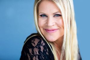 Close-up beauty portrait featuring black lace top against blue background.