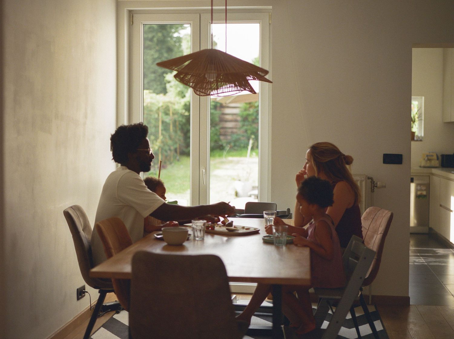 Sunny outdoor scene of parent and baby sharing a tender moment at a table.