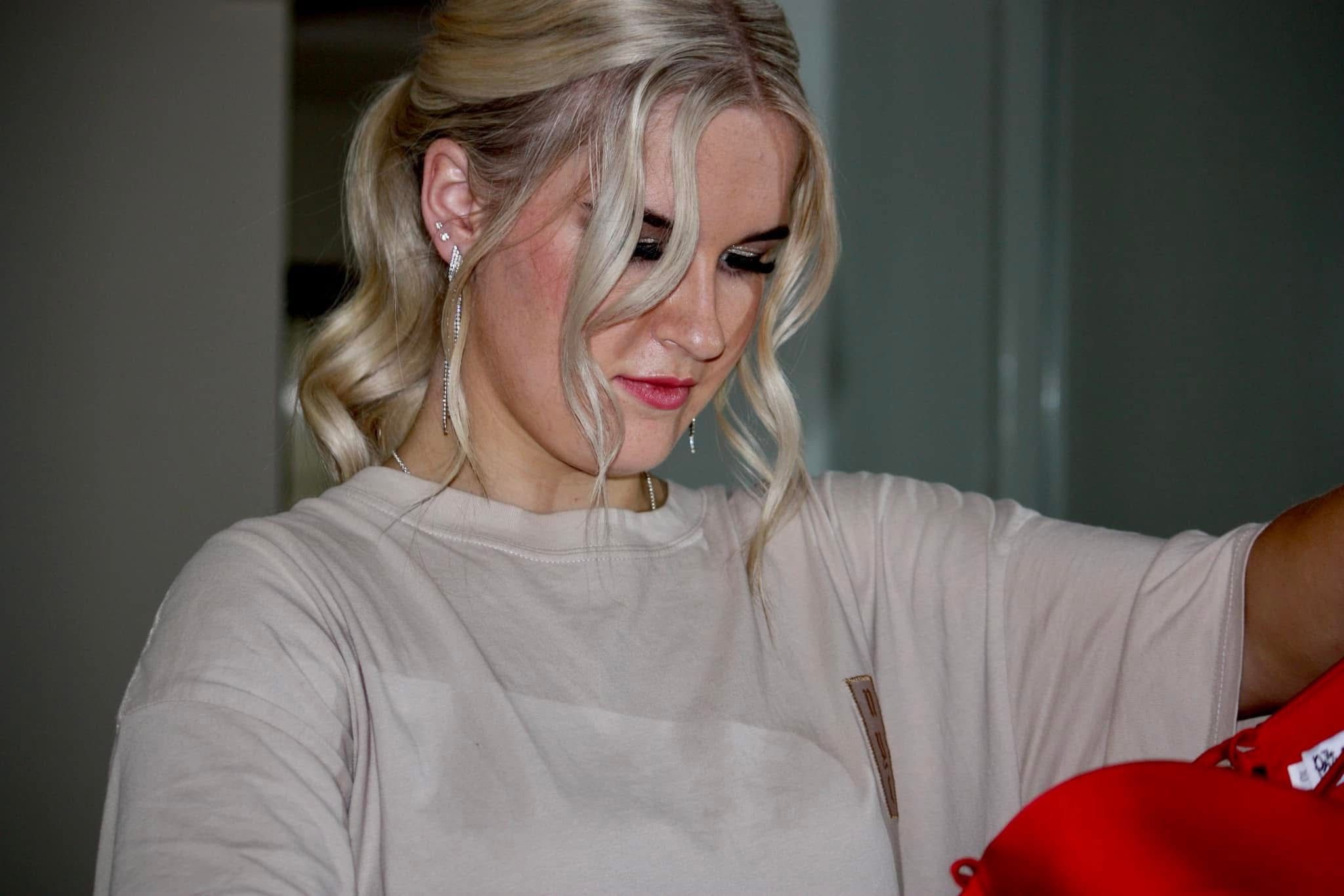 A person in casual attire smiles while standing indoors.