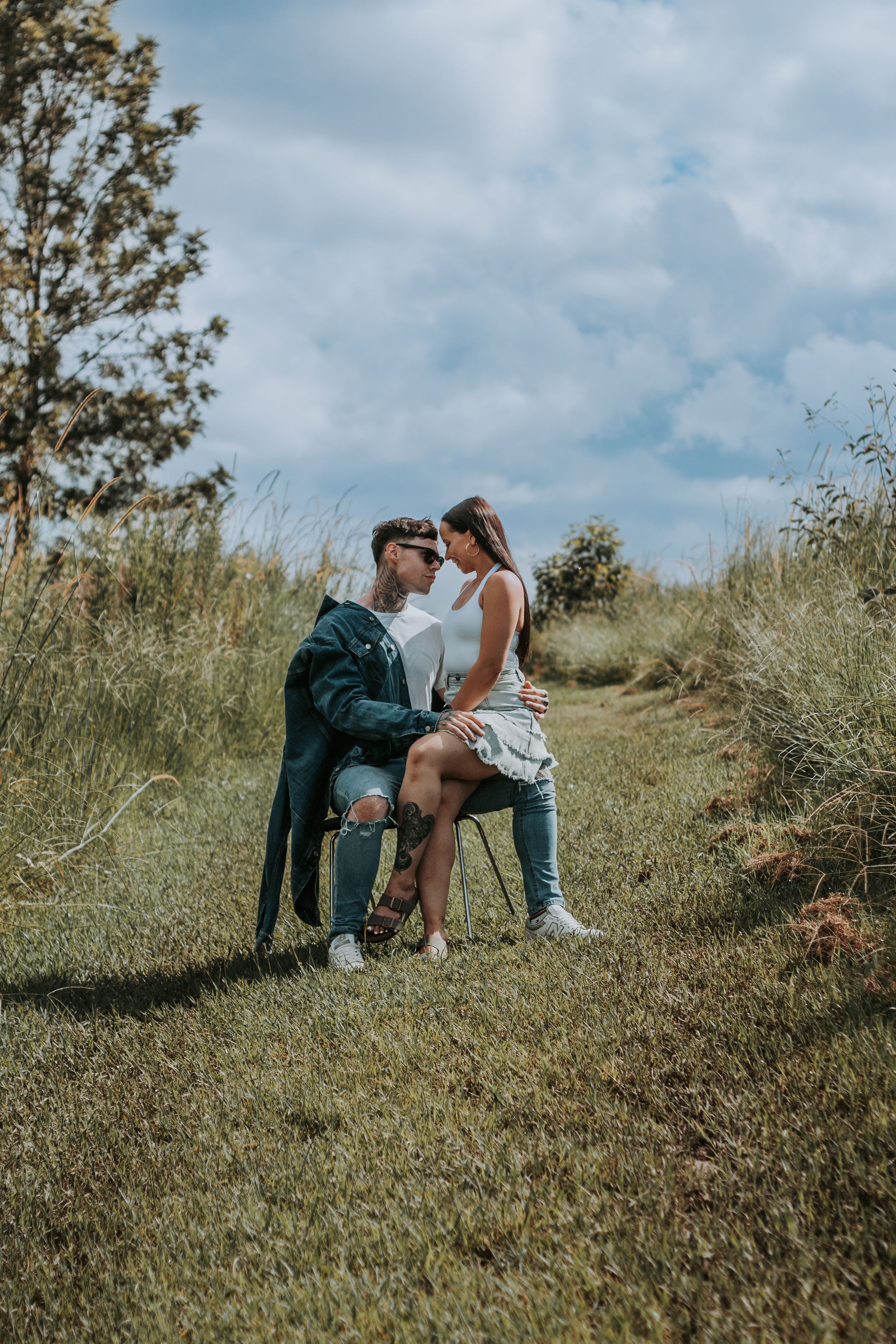 A romantic couple shares an intimate moment while sitting outdoors in nature.