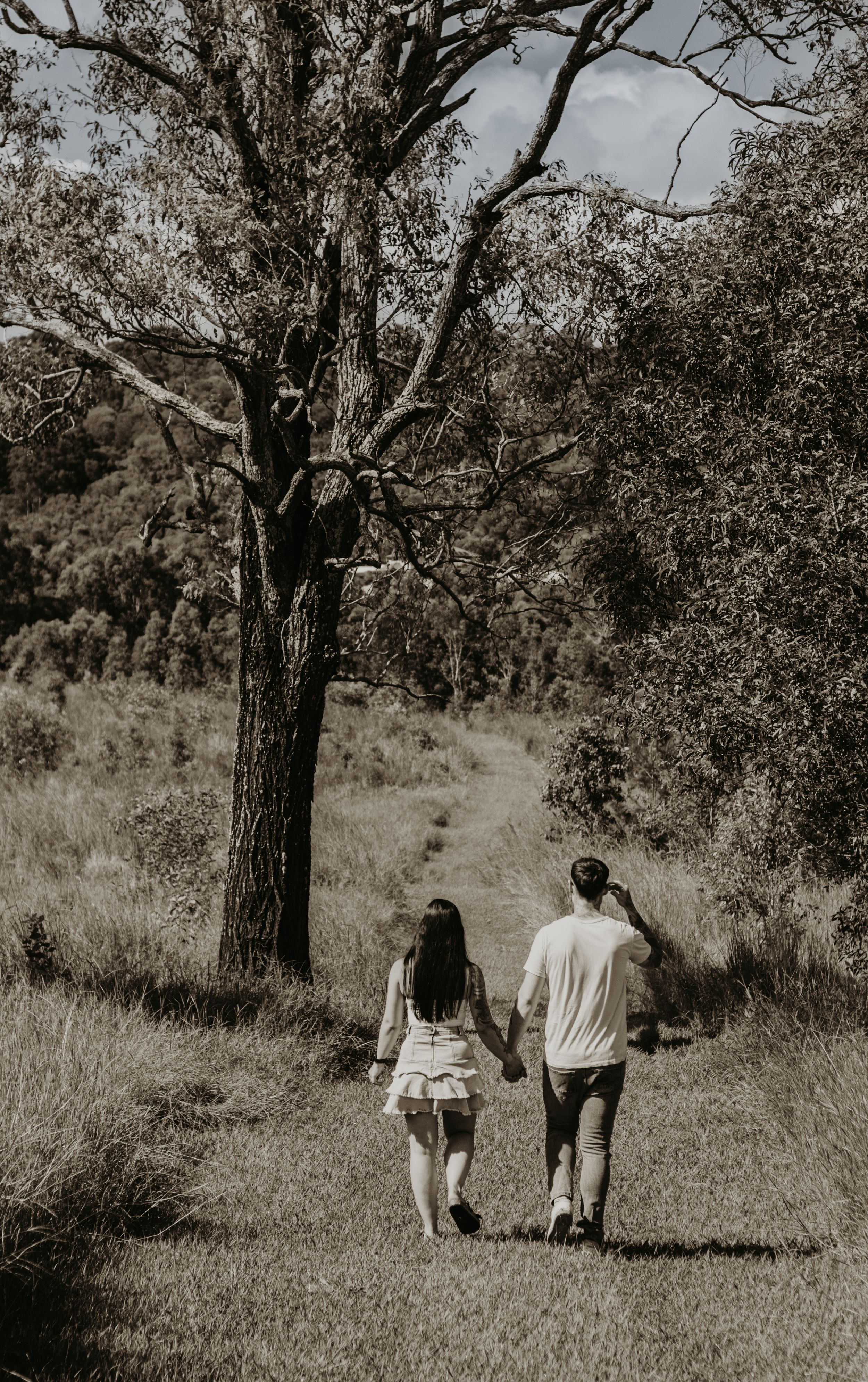 A couple walks away down a nature trail in black and white.