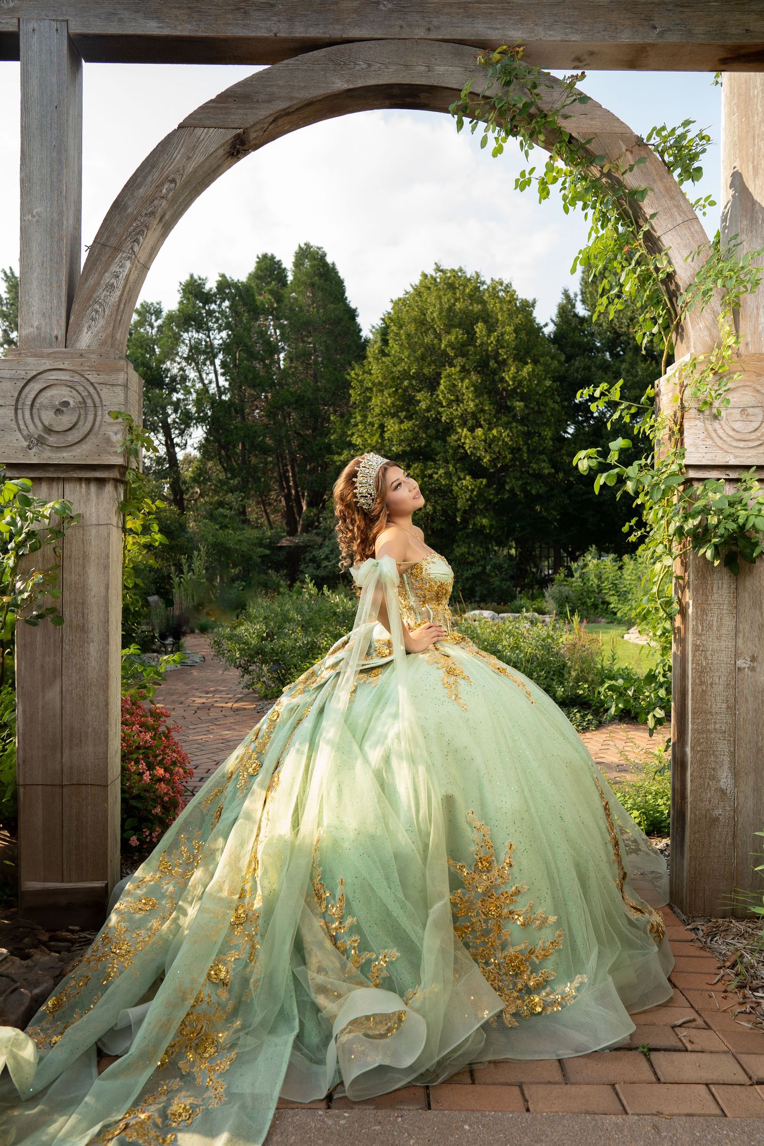 A stunning gold and champagne colored ballgown with intricate beading sparkles in outdoor portrait lighting.
