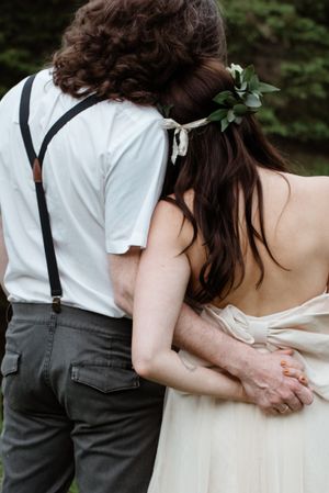 A close-up view of a couple in wedding attire with suspenders and floral hair accessories.