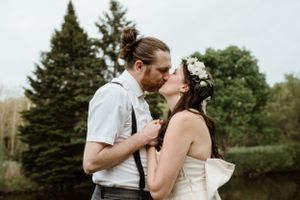 Romantic outdoor wedding portrait with evergreen trees and natural scenery in the background.