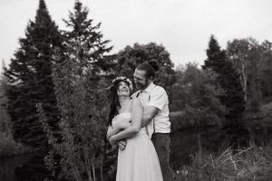 Black and white portrait of a romantic couple embracing outdoors among evergreen trees.