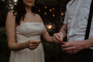 Couple holds sparklers creating magical light in evening wedding celebration.
