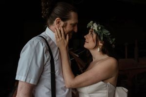 Intimate moment between newlyweds in a soft low light setting with delicate gestures and romantic atmosphere.