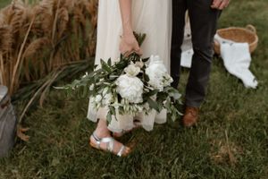 Detail shot of white floral bouquet and dress hem against natural pampas grass backdrop taken on photography basic course and retreat