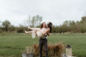 A joyful lift pose in a green meadow with rustic decor elements.
