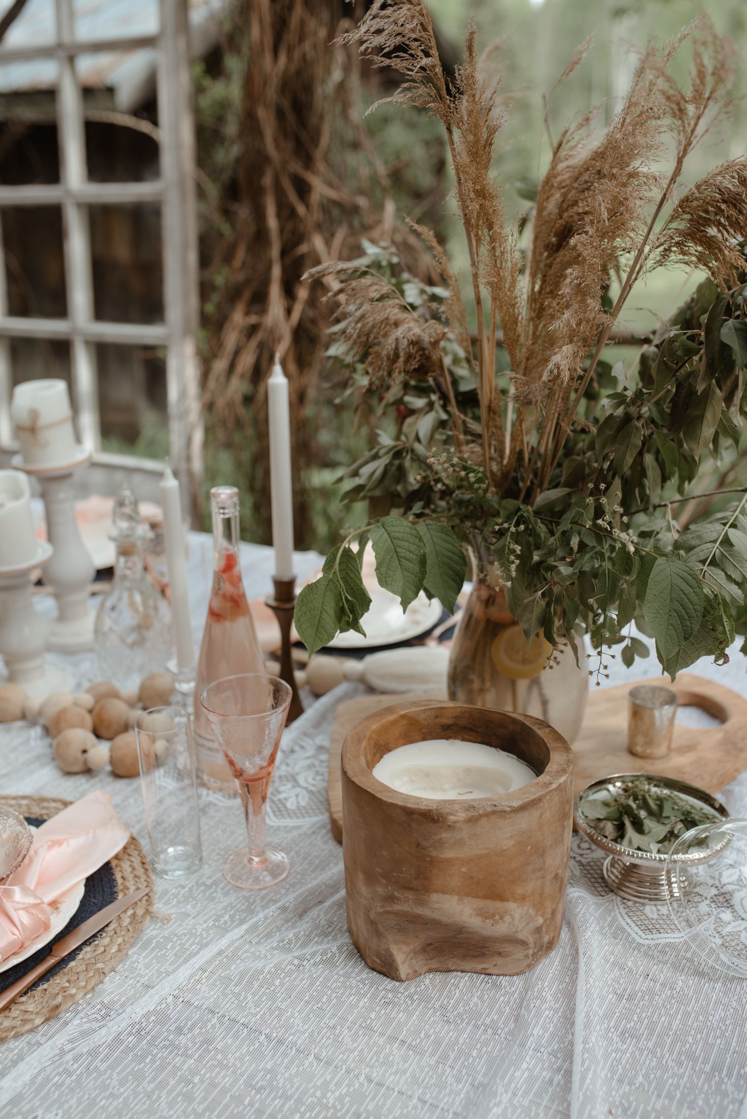 Rustic table setting with pampas grass centerpiece and blush pink glassware.