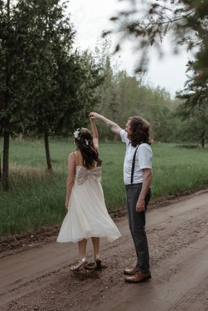 A couple shares a dancing moment on a tree-lined country road.