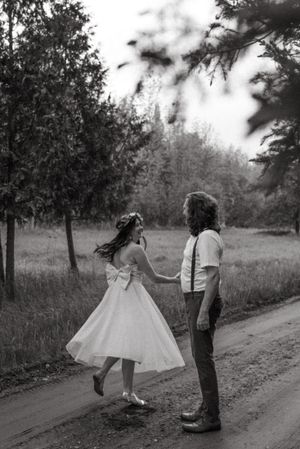 A black and white photo of a couple dancing on a rural dirt road.
