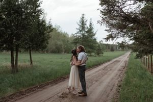 A tender embrace on a country road surrounded by spring greenery.