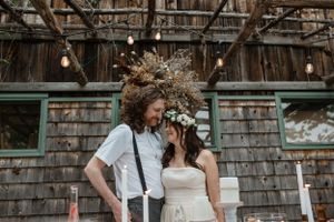 Rustic barn wedding portrait with string lights and natural wooden backdrop.