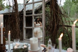 Candlelit wedding decor with couple visible through a vintage window frame.