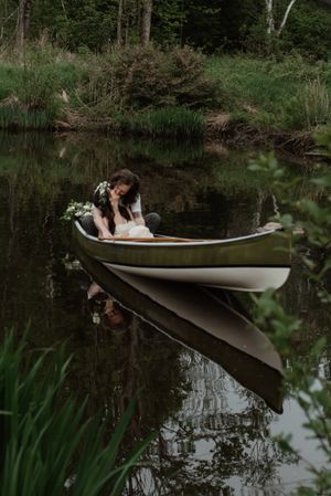 Intimate moment captured in a canoe on a reflective pond surrounded by wilderness.