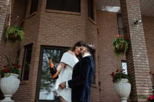 Elegant couple in formal attire sharing romantic moment against brick building exterior.