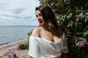 White dress against flowering bush with lake view in background.
