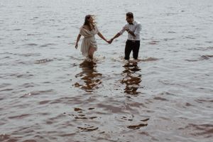Two people splashing and playing together in shallow ocean water.