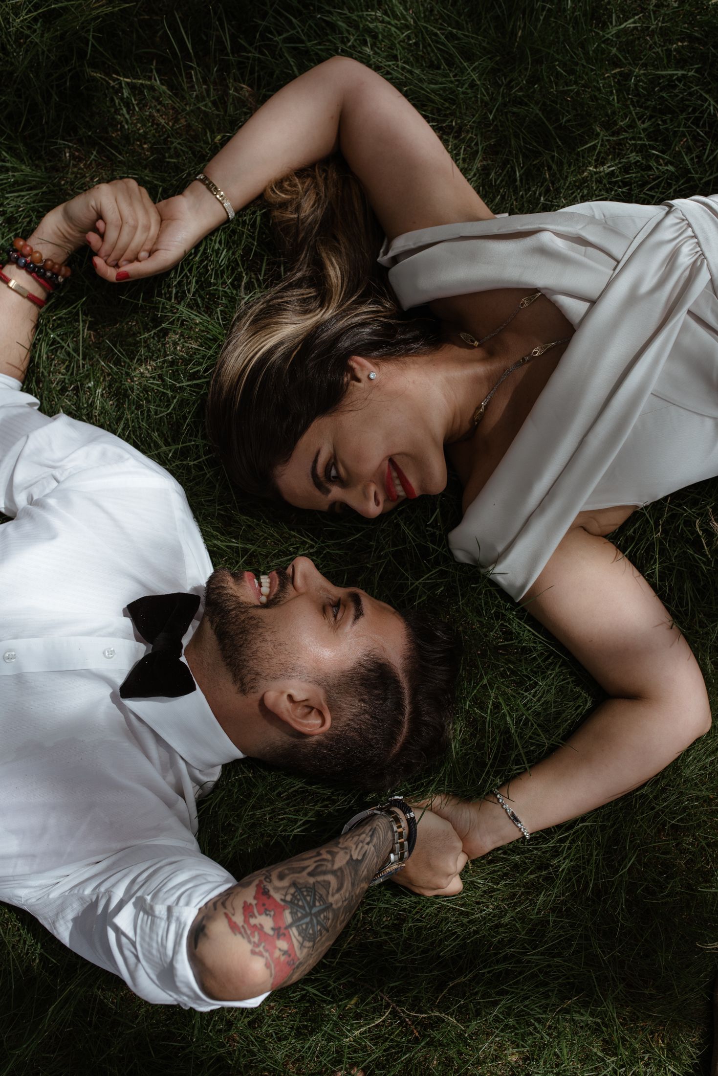 Two people lying on grass sharing a candid laughing moment together.