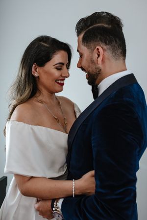 Intimate moment between couple in formal wear against white background.