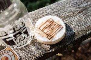 Close-up of wooden photography branding coasters with camera logo designs.