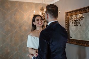 A tender moment between a couple in formal wear standing in a luxurious interior setting.