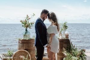 Intimate moment between couple at oceanside ceremony with rustic decor.
