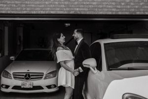 Couple sharing a romantic moment by a Mercedes-Benz car in black and white.