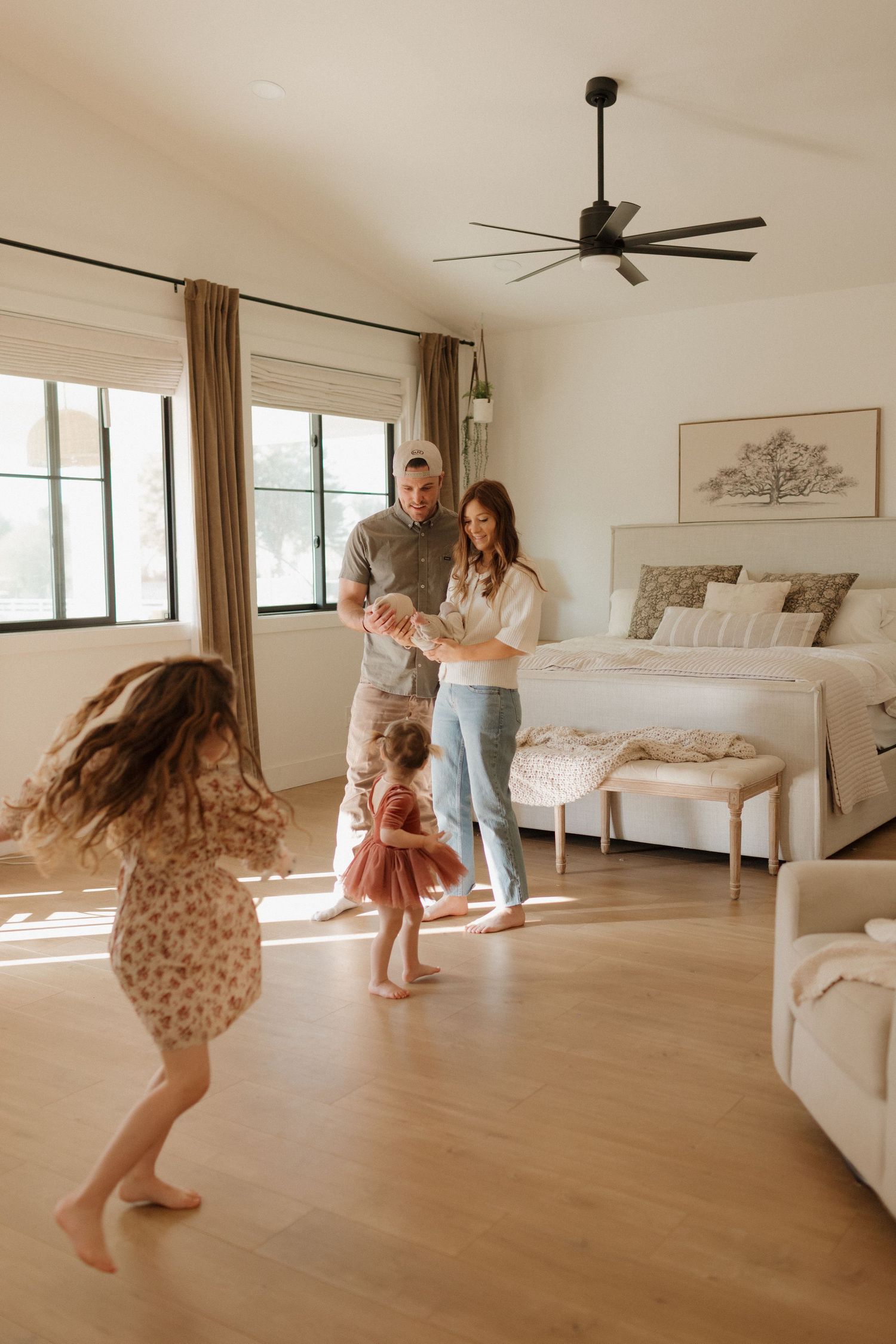 A joyful family moment in a bright bedroom with hardwood floors and natural light.