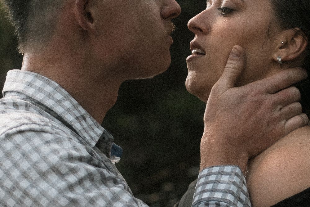 A couple shares an intimate moment, with a man gently holding a woman's face as they lean in close together.