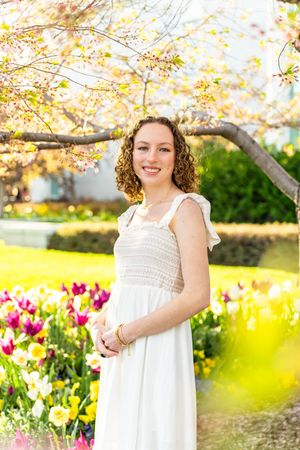 Spring portrait of a girl in a white dress surrounded by blooming tulips and blossoms at mount timpanogos temple in American Fork, Utah.