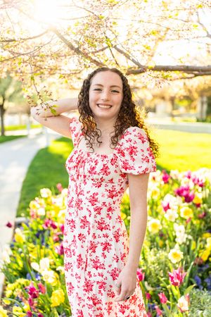 A red floral dress styled for spring against a backdrop of tulips and flowering trees at mount timpanogos temple in American Fork, Utah.