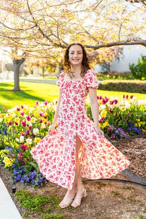 A girl in a floral red and white dress in a garden setting with colorful tulips at mount timpanogos temple in American Fork.