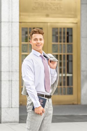 A missionary holding the Book of Mormon in front of the doors of the Draper Utah temple in Draper, Utah.