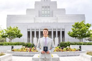A missionary holding the Book of Mormon in front of the Draper Utah temple in Draper, Utah.