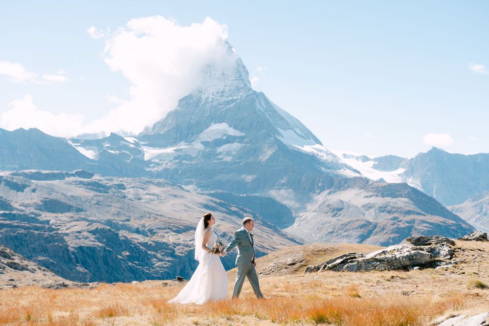 Two people twirl together on a golden hillside with the majestic Matterhorn mountain peak rising in the distance.
