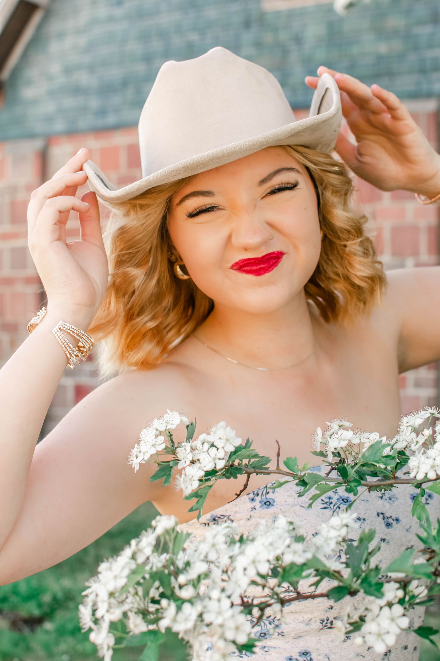 Portrait with white cowboy hat and floral dress surrounded by delicate white blossoms.