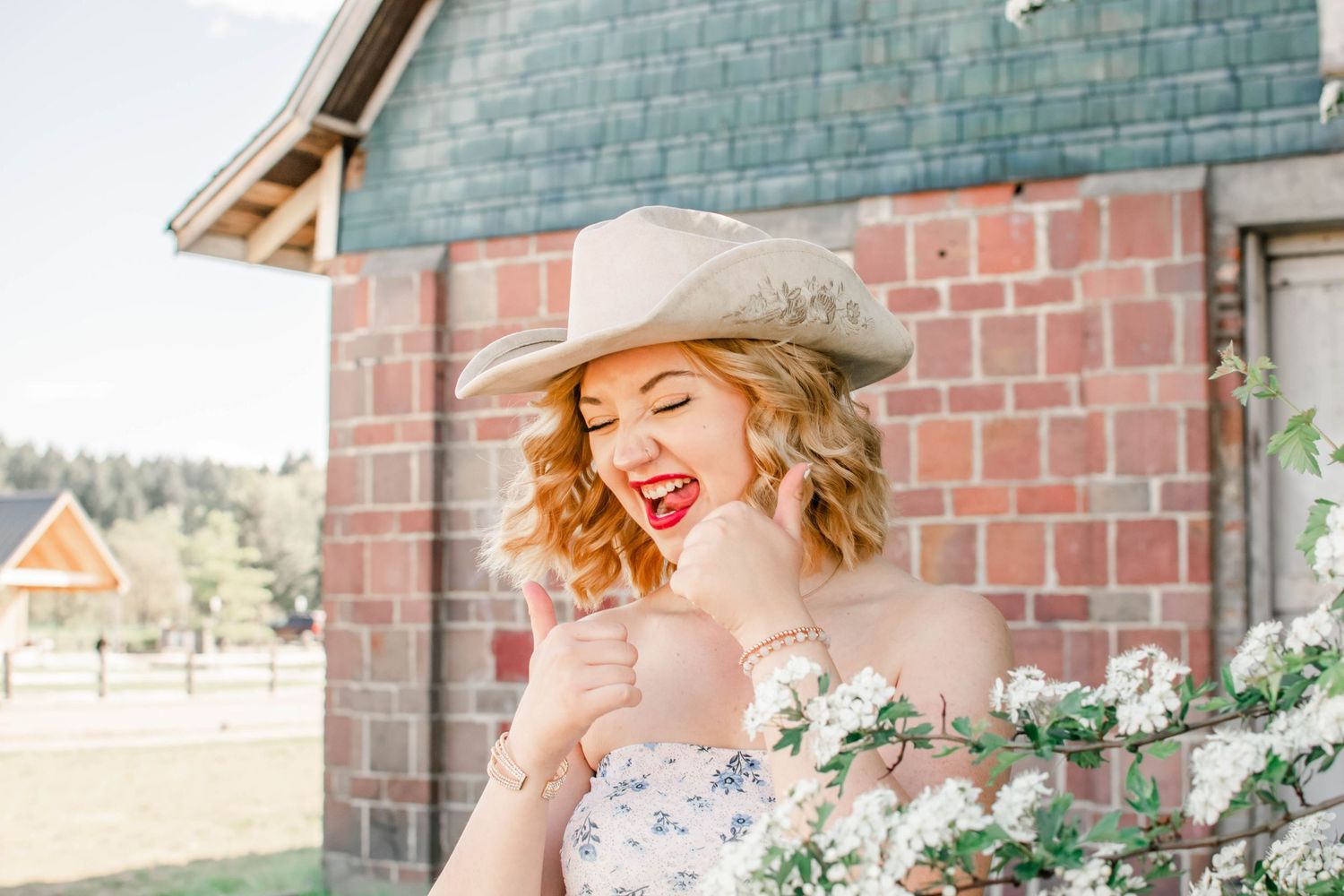 Outdoor fashion photography featuring floral dress and western style hat against architectural backdrop.