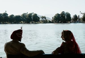 Five silhouettes of people stand against a serene lake backdrop during sunset hours creating a peaceful scene.