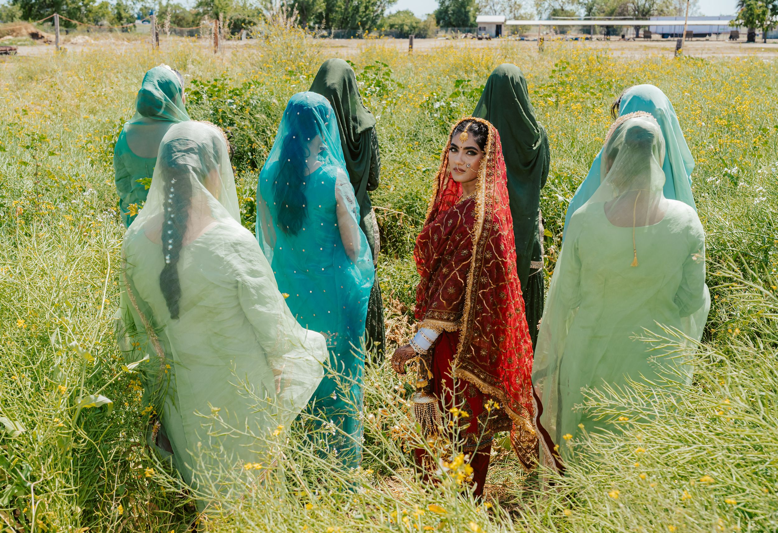 People in protective suits and masks inspect plants and crops in a sunny green field during agricultural work.