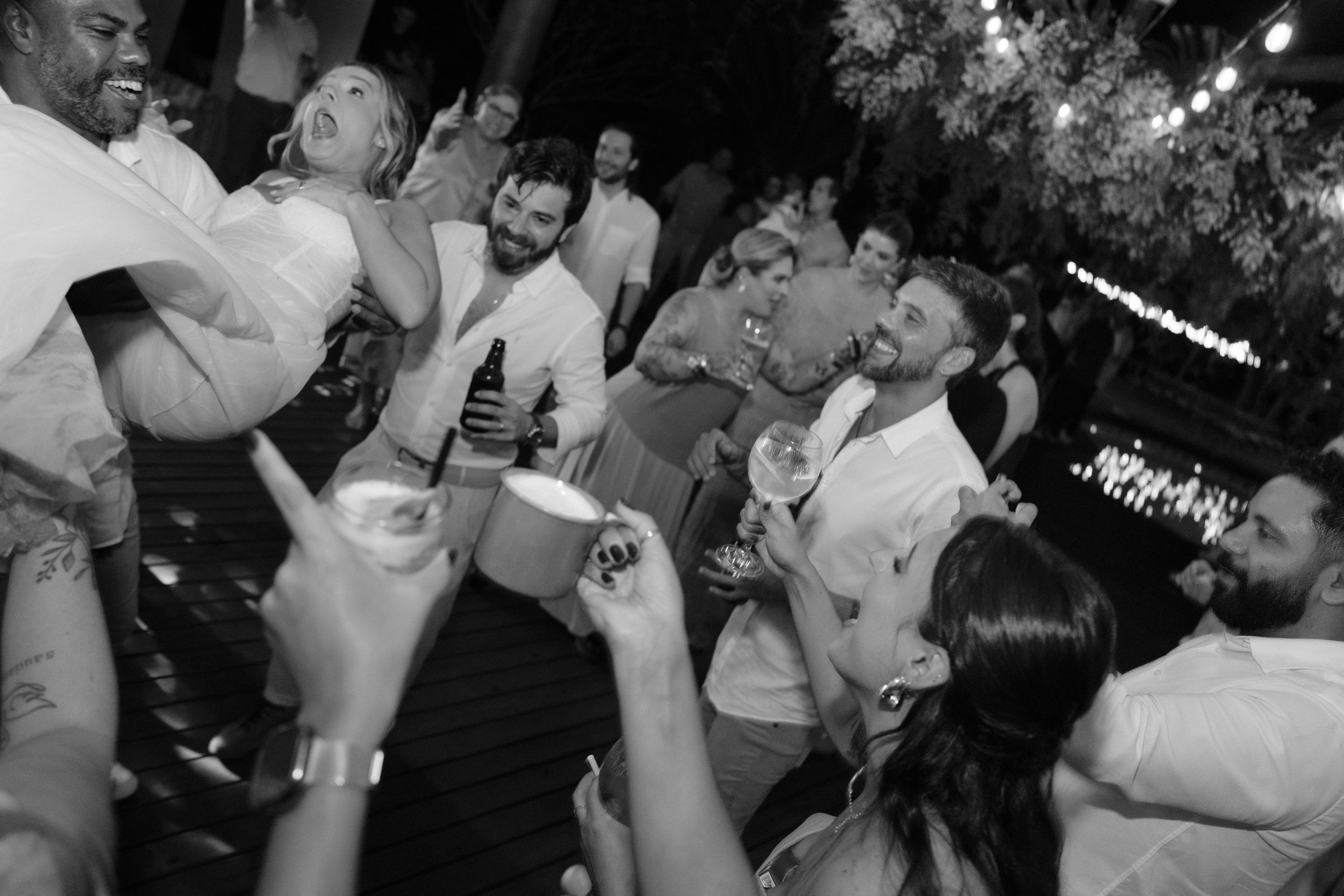 Black and white photo of energetic dance party with crowd celebrating at nighttime event.
