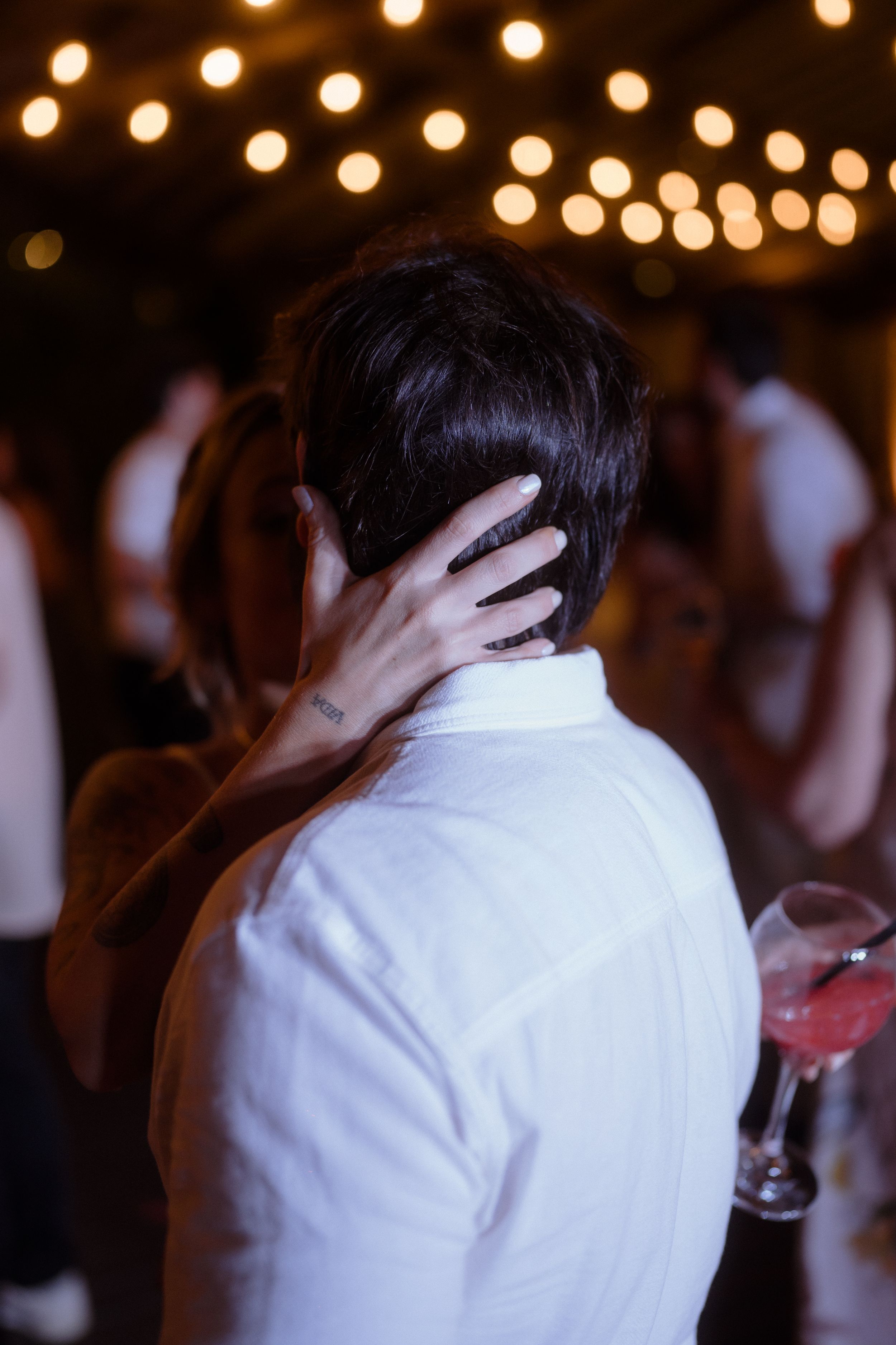 Intimate dance moment captured under warm string lights at an evening celebration.