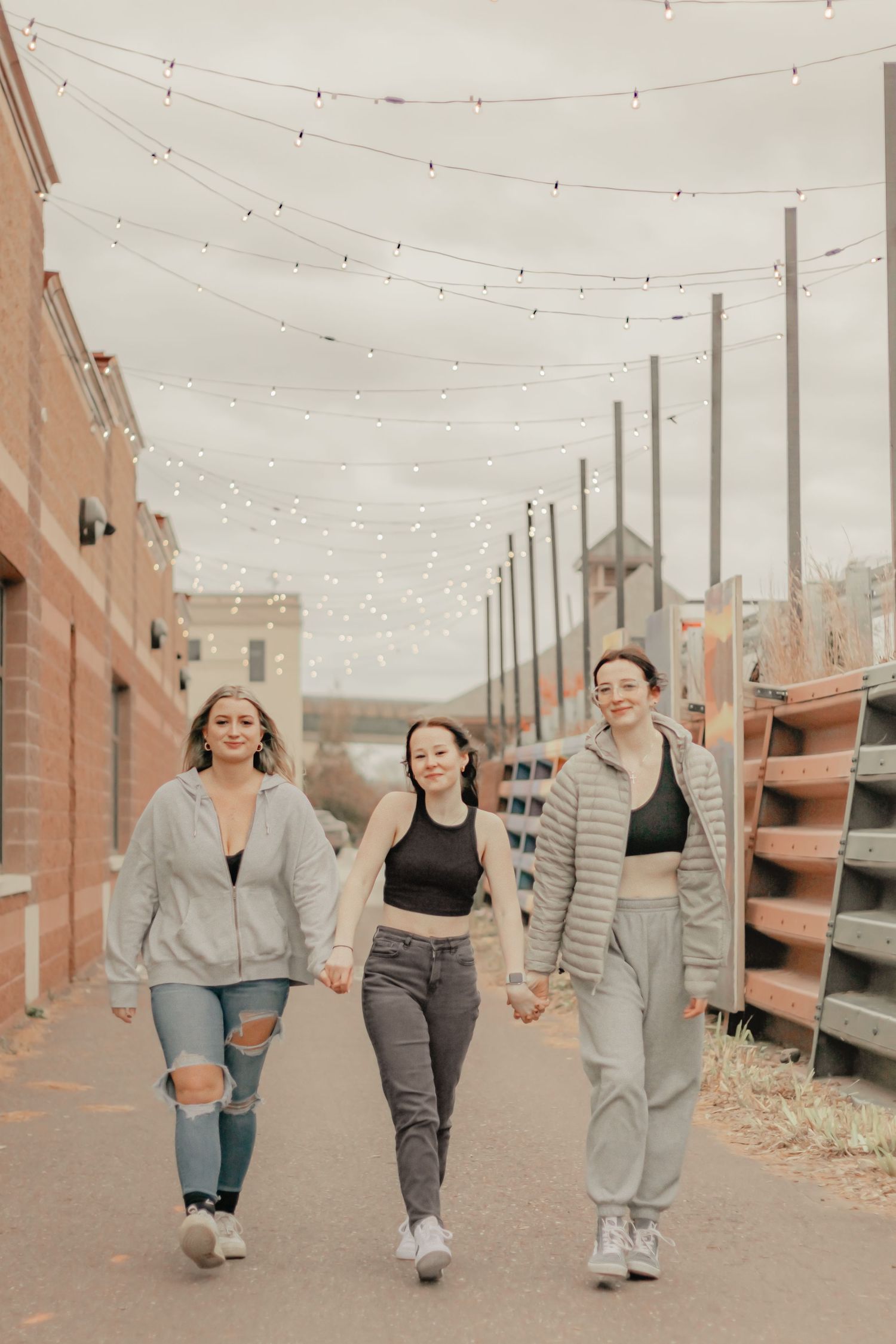 Three friends walking together under string lights in Houghton, Michigan.