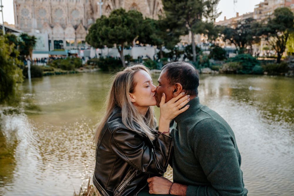 Deepak and Julia holding hands in front of Sagrada Família on a sunny winter afternoon.