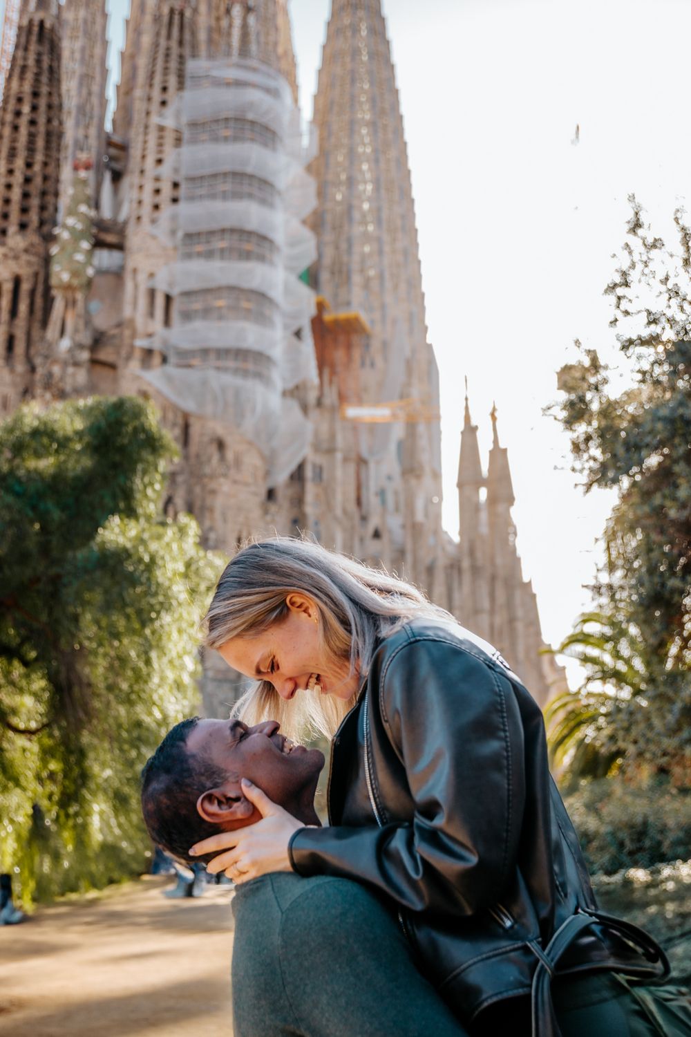 Couple framed by the trees outside Sagrada Família with soft winter light.